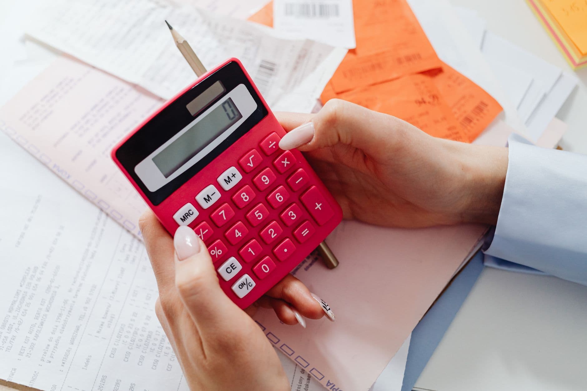 Hands using a calculator beside financial paperwork